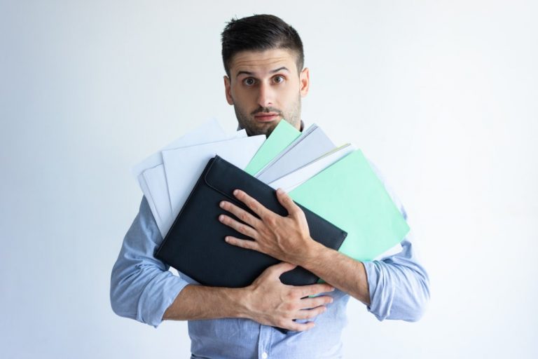 puzzled-office-worker-holding-pile-documents-min
