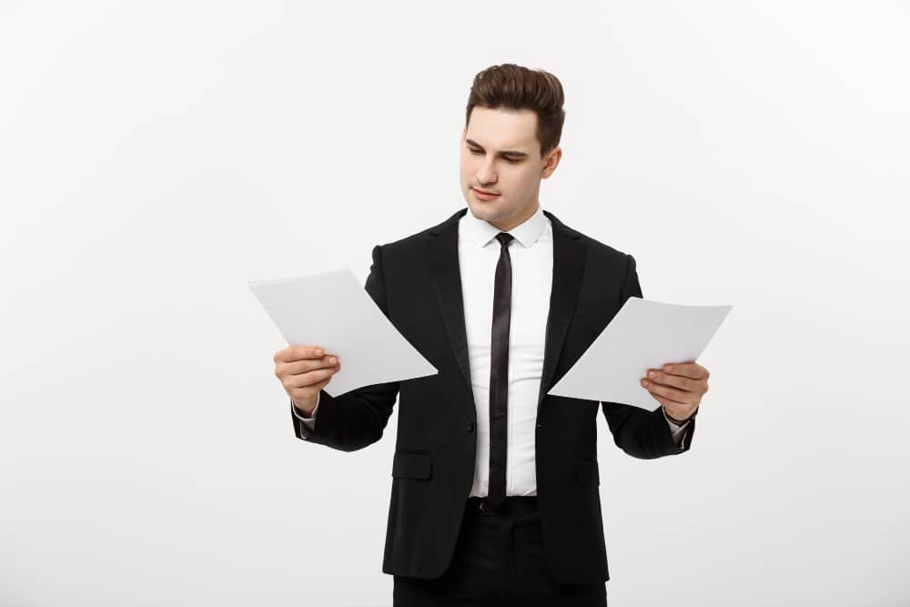 business-concept-attentive-handsome-businessman-working-comparing-paper-report-isolated-white-grey-background